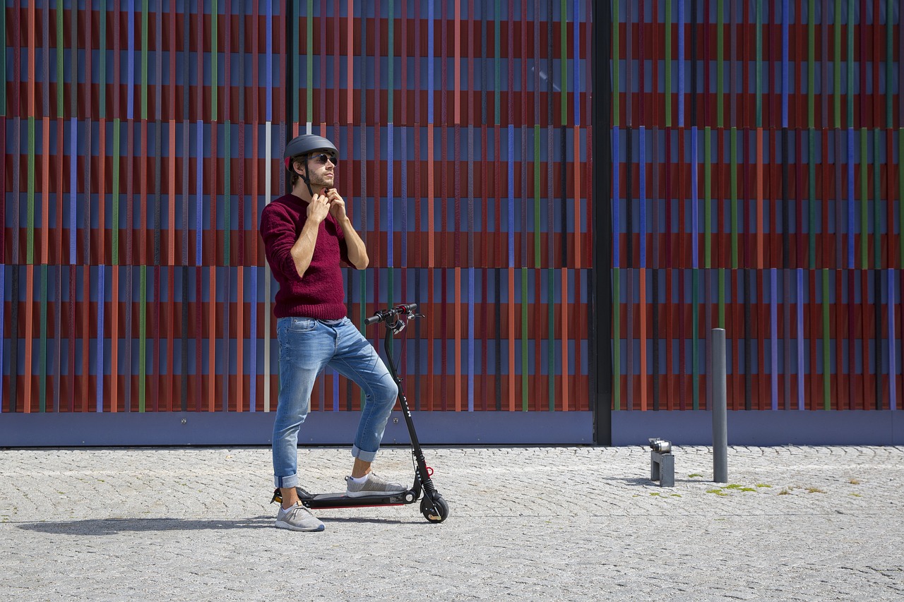 man is going to ride electric scooter on the colorful wall background