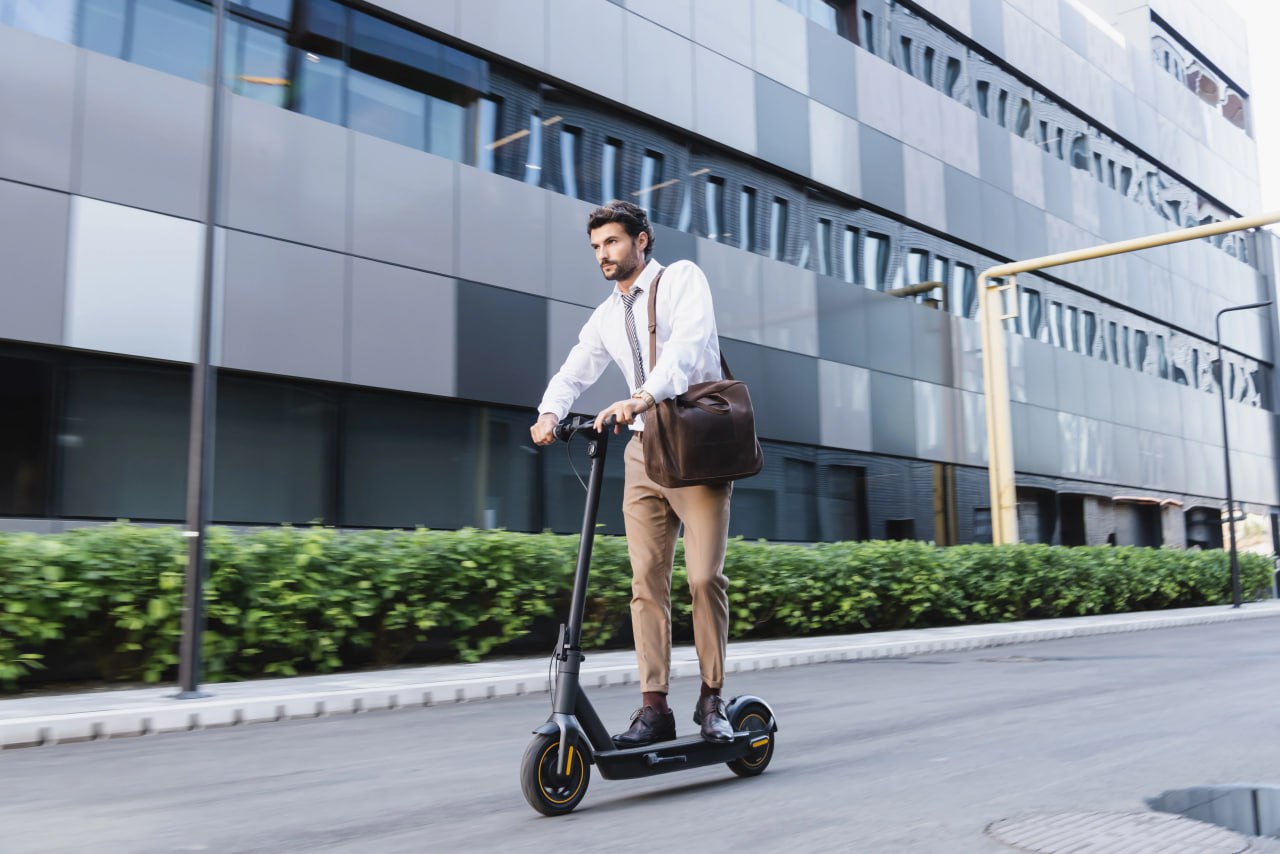 man is ridding e-scooter for a work near business center