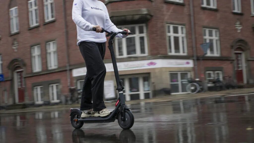 person riding electric scooter with features on the rain road