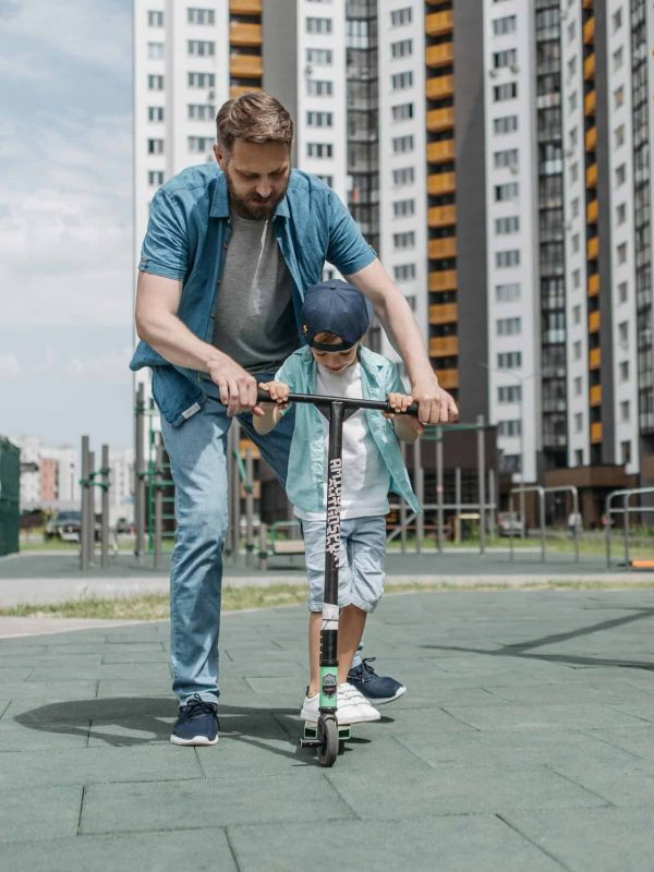 father teach his son how to ride electric scooter for kids